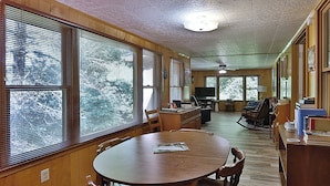 A cozy living room with a wooden dining table, chairs, a television, and a rocking chair. - Smoky Mountain Getaway. Enjoy Seclusion,Views,Motorcycling, Shops w Paved Access (Franklin)