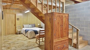 A bedroom with a wooden staircase, a bed, a chair, and a wooden cabinet. - Smoky Mountain Getaway. Enjoy Seclusion,Views,Motorcycling, Shops w Paved Access (Franklin)