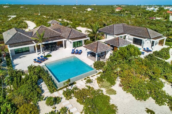 Ein modernes Resort mit mehreren Villen, einem zentralen Pool und üppiger tropischer Landschaft.