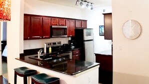 A modern kitchen with dark wood cabinets, stainless steel appliances, and a central island with bar stools. - Upscale stay 2.5 blocks to Kierland and Scottsdale Commons shopping.   (Scottsdale)