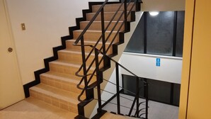 A staircase with black railings and beige steps, leading to a landing with a blue sign. - HOTEL Sunset Marino - Adults Only (Chatan)
