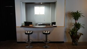 A reception area with a reception desk, two checkered stools, a potted plant, and a window. - HOTEL Sunset Marino - Adults Only (Chatan)