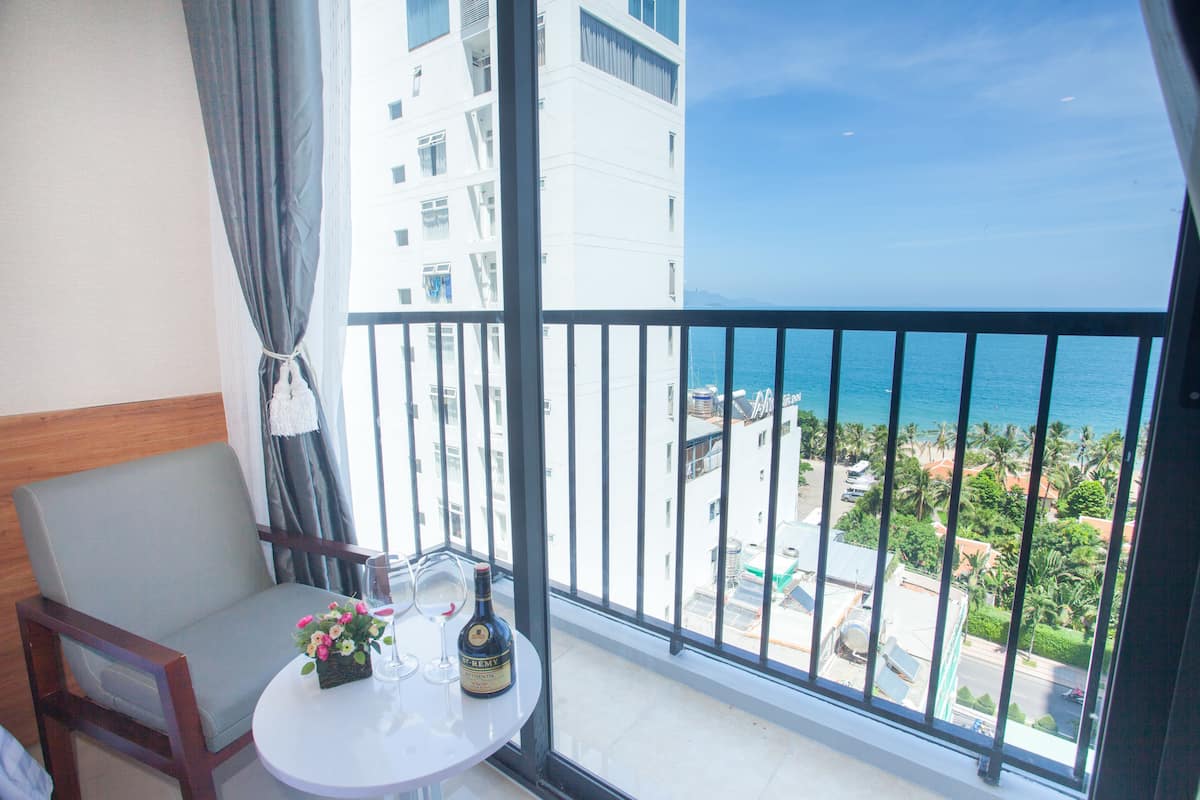 A balcony with a view of the ocean and a building in the background.