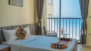 A hotel room with a bed, a small table with a bottle and glasses, and a view of the sea through large windows. - Ecstasy Hotel (Nha Trang)