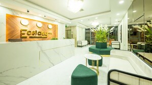 A modern hotel lobby with a reception desk, green seating, and a chandelier. - Ecstasy Hotel (Nha Trang)