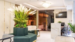 Una sala moderna con un sofá verde, una mesa de centro redonda y una planta grande en maceta.