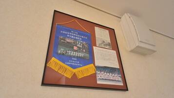 A bulletin board with framed pictures and text, a white air conditioning unit, and a beige wall.