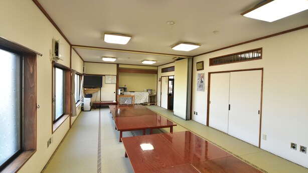 A traditional Japanese-style room with tatami flooring, sliding doors, and a long wooden table.