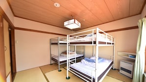 A room with bunk beds, a heater, and tatami mats.