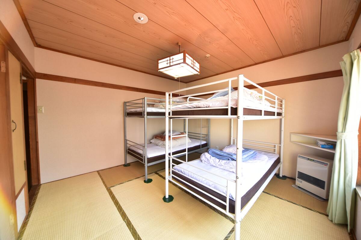 A room with bunk beds, a heater, and tatami mats.