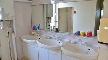 A bathroom with two sinks, a mirror, and a shower.