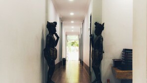 Un pasillo con dos estatuas a cada lado, un banco de madera con libros y un cesto de basura.