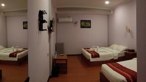 Habitación de hotel con dos camas, una mesita pequeña, televisor y aire acondicionado instalado en la pared.