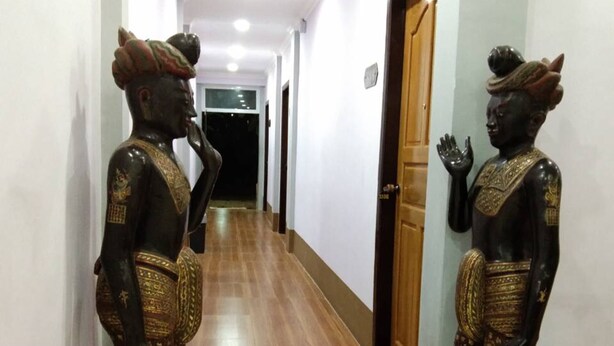 Un pasillo con piso de madera y dos estatuas de figuras con vestimenta tradicional.