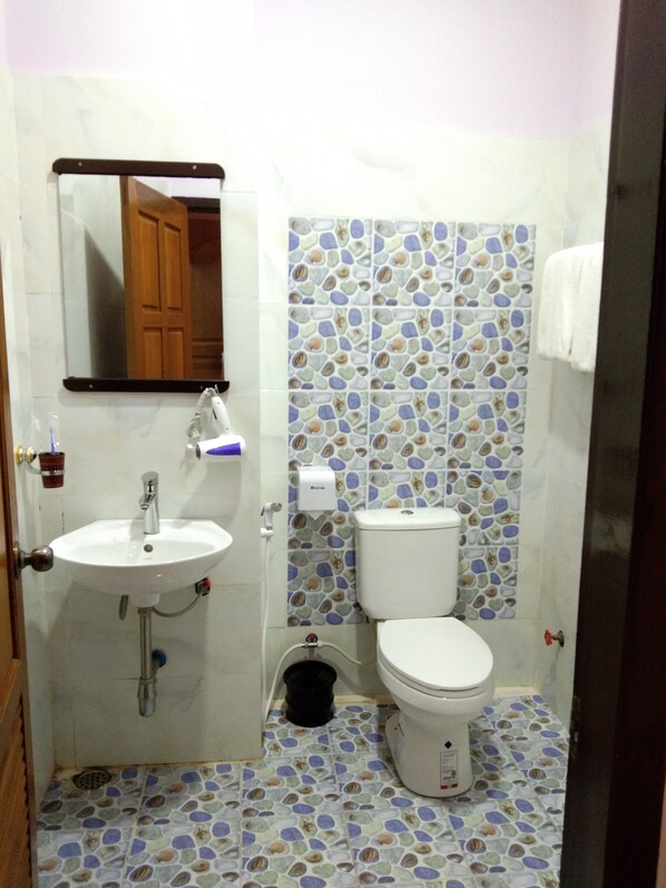 Un baño con un lavamanos blanco, un espejo, un inodoro y un suelo estampado.