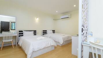 Ein Hotelzimmer mit zwei Betten, einem Schreibtisch, einem Stuhl, einem kleinen Tisch und einer Klimaanlage.