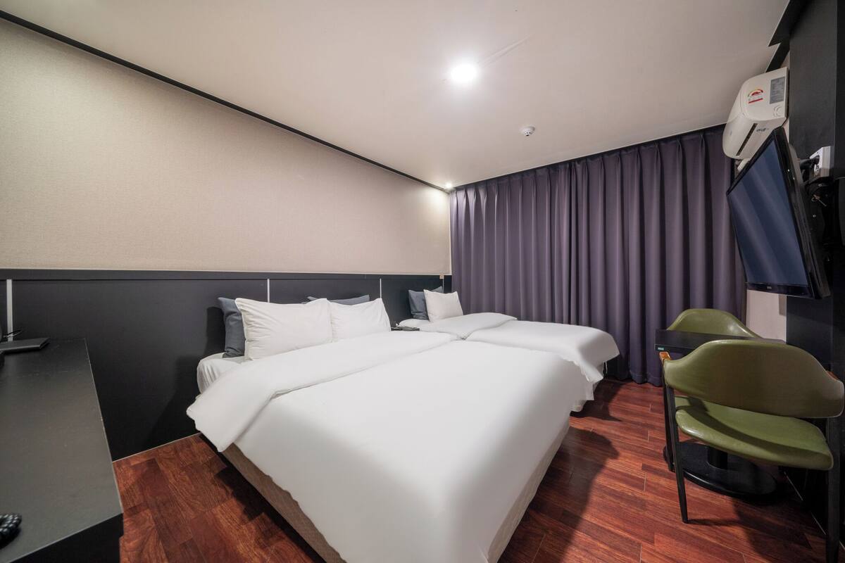 A hotel room with a large bed, a desk, and a chair.