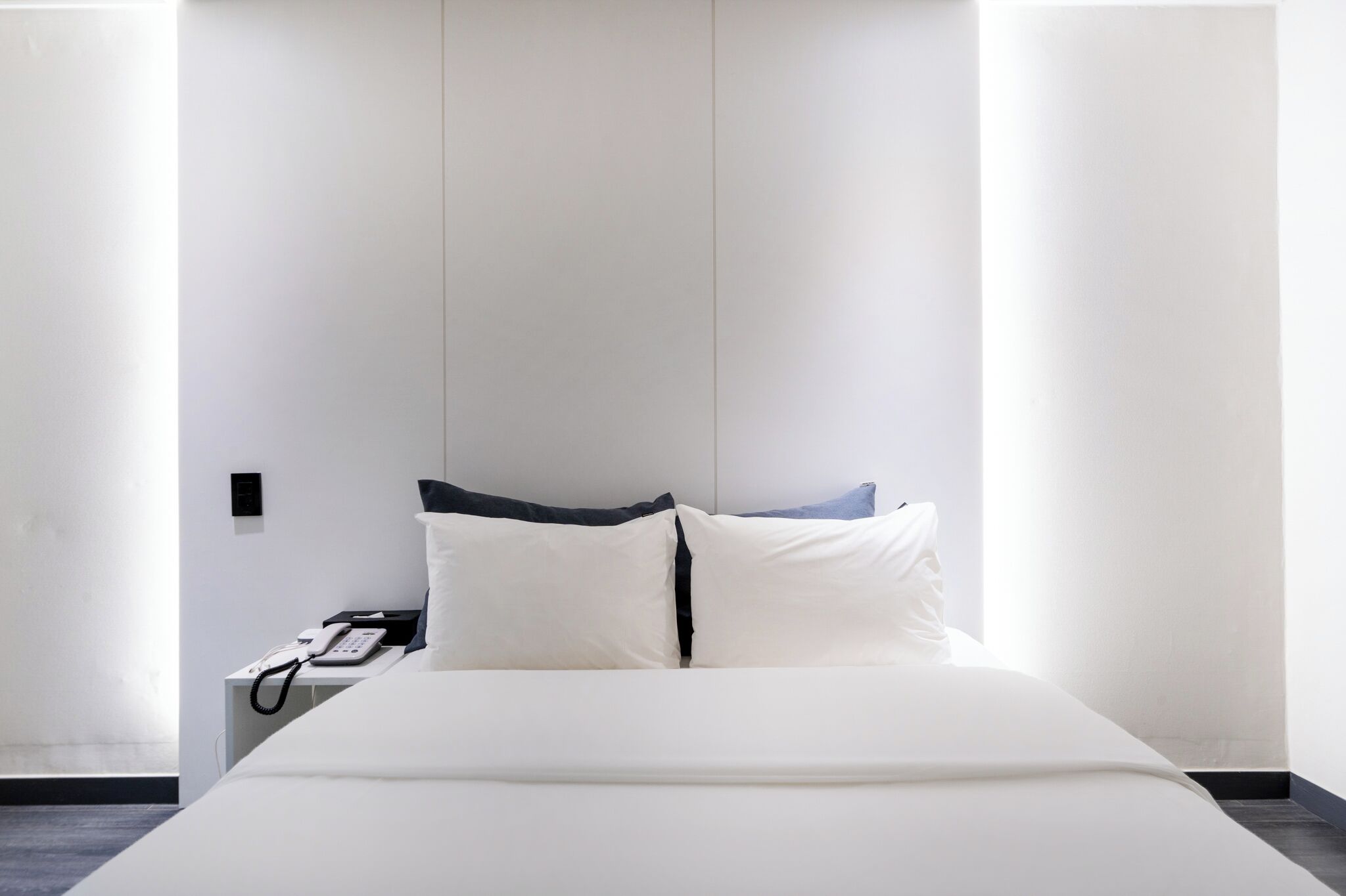 Een hotelkamer met een bed, een bedtafeltelefoon en een wandlamp.