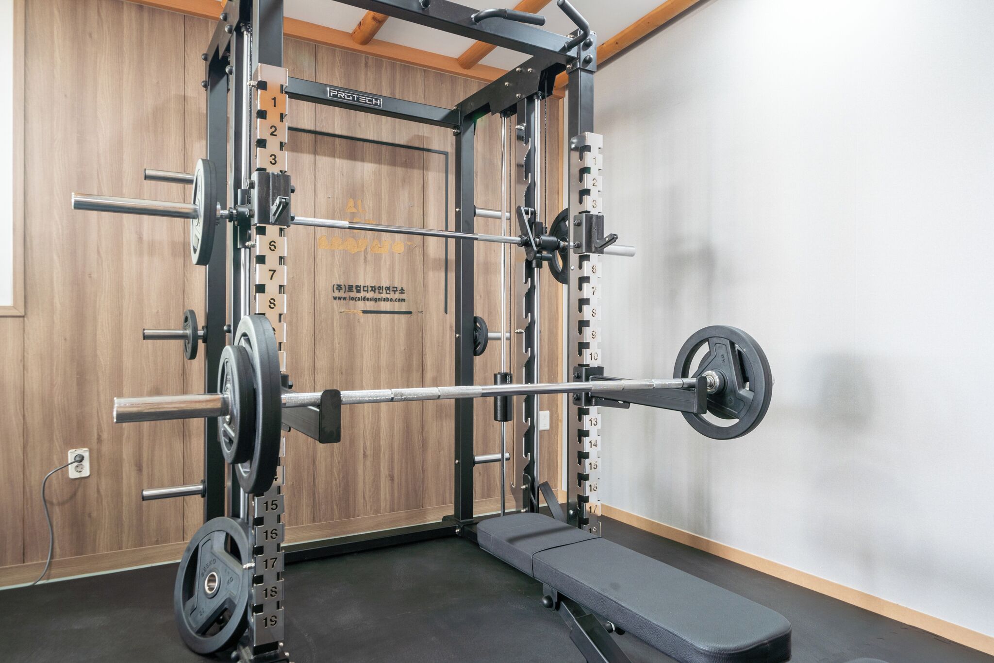 A gym with a squat rack, bench, and weight plates.