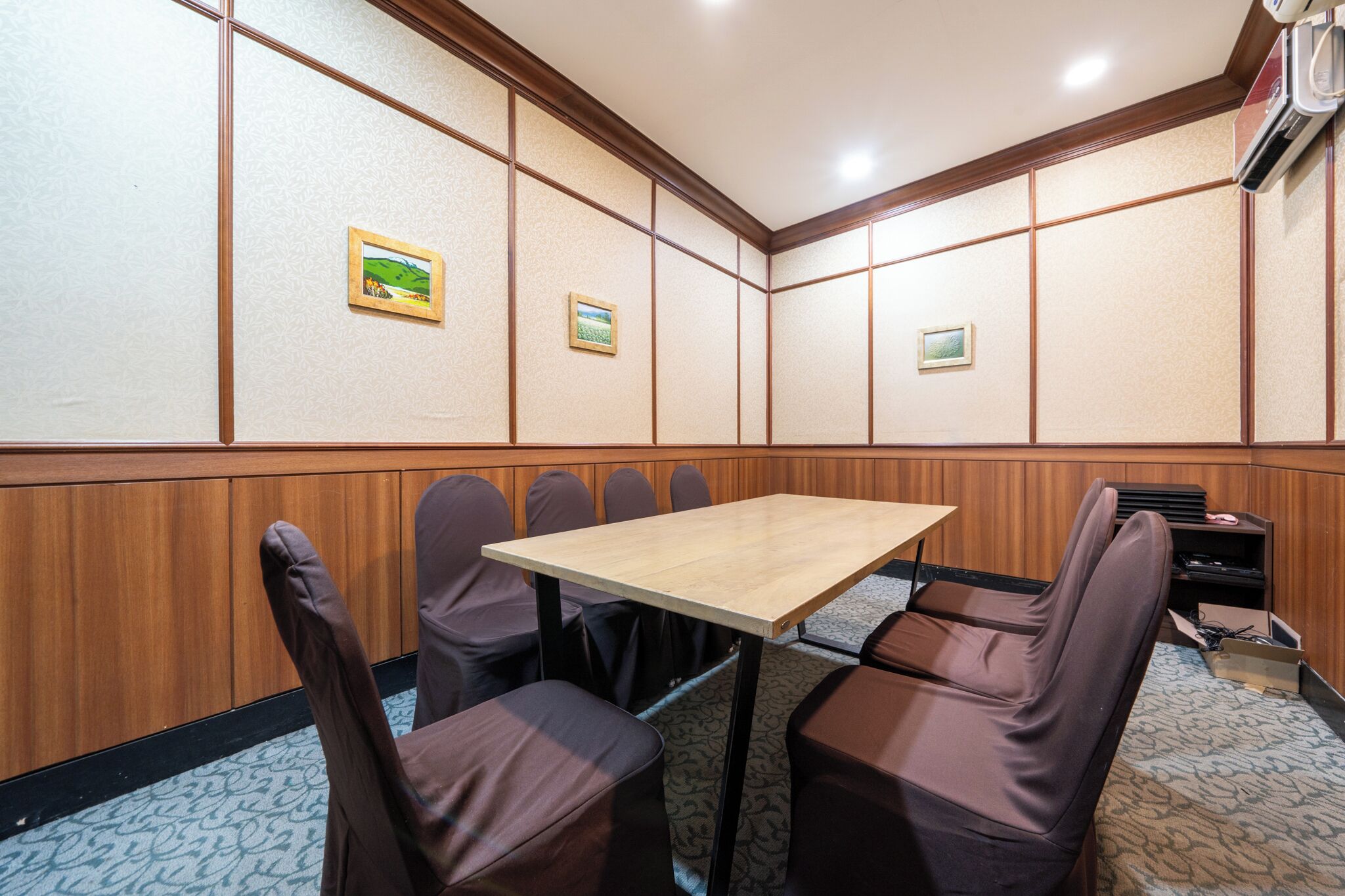 Una sala de conferències amb una taula de fusta i sis cadires marrons.