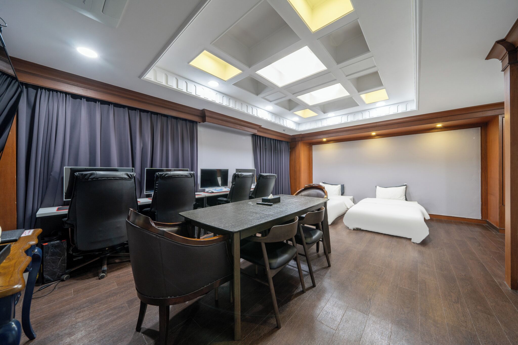 A hotel room with a large bed, a desk with computers, and a seating area with chairs.
