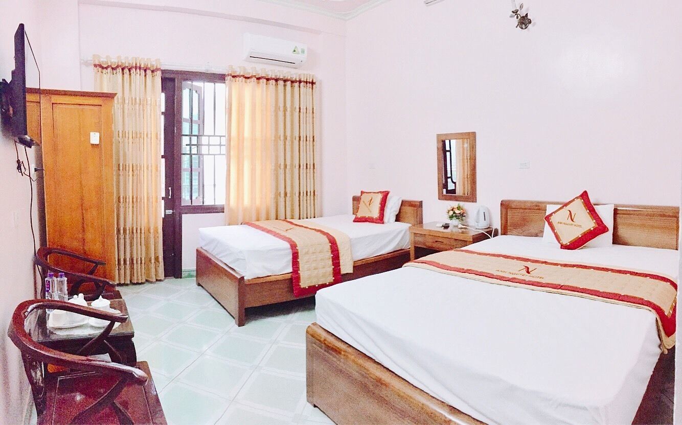 A hotel room with two beds, a desk, a chair, and a wardrobe.