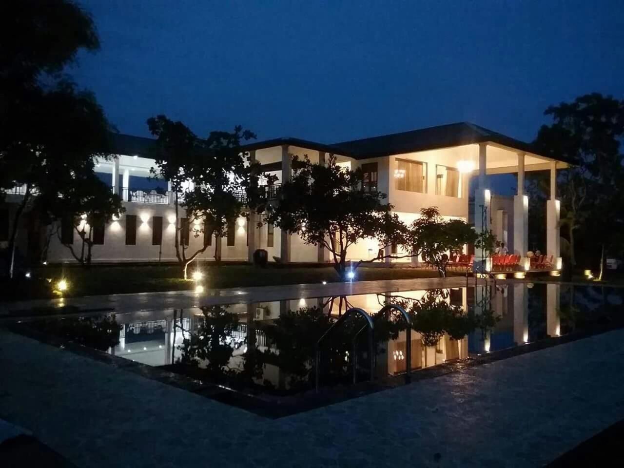 Een hotel met een zwembad, terras en een goed verlichte gevel.