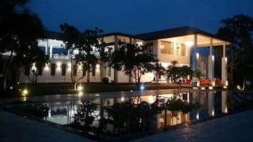 A hotel with a pool, outdoor seating, and a well-lit facade.