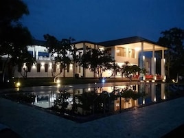 Un hotel con piscina, mobiliario exterior y fachada bien iluminada.