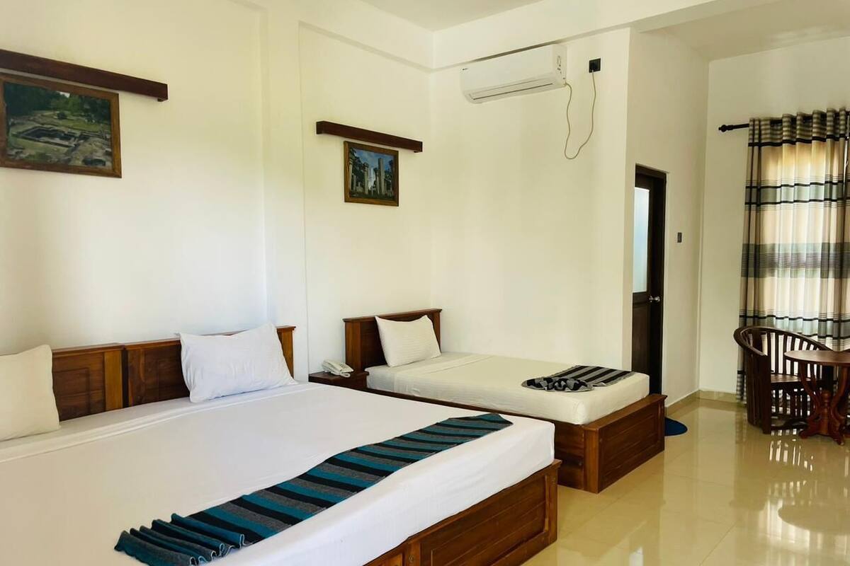 Een hotelkamer met twee bedden, een eethoek en een airconditioning.