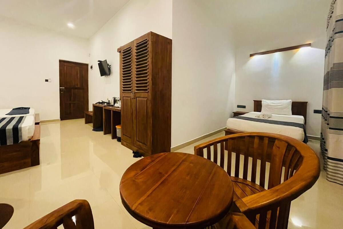 Een hotelkamer met een bed, een houten garderobe, een ronde houten tafel en een stoel.