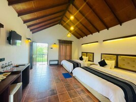 Habitación de hotel con dos camas, un escritorio con televisor y un balcón.