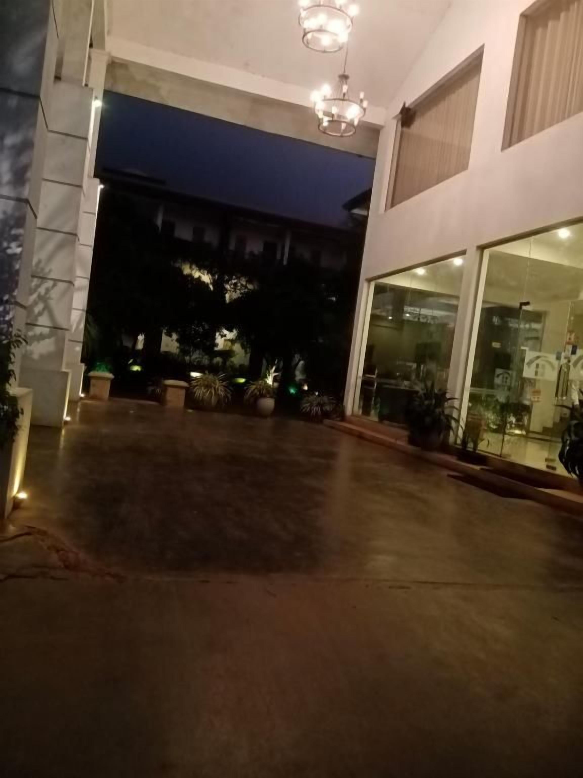Spazio esterno con pavimento in cemento, ingresso con porta in vetro e lampadario.