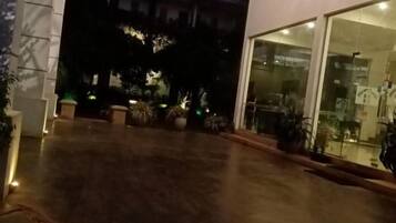 Spazio esterno con pavimento in cemento, ingresso con porta in vetro e lampadario.