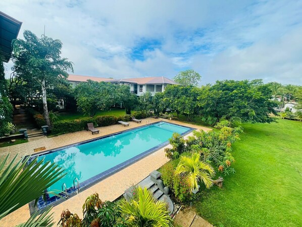 A rectangular swimming pool with a tiled edge, surrounded by a well-maintained lawn and various tropical plants. - Four Points Resort - Anuradhapura (Anuradhapura)