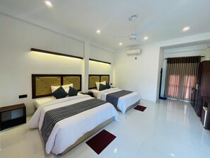 A modern hotel room with two beds, a ceiling fan, and a large window with curtains. - Four Points Resort - Anuradhapura (Anuradhapura)