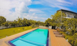 A swimming pool with a surrounding garden and a building with a balcony. - Four Points Resort - Anuradhapura (Anuradhapura)