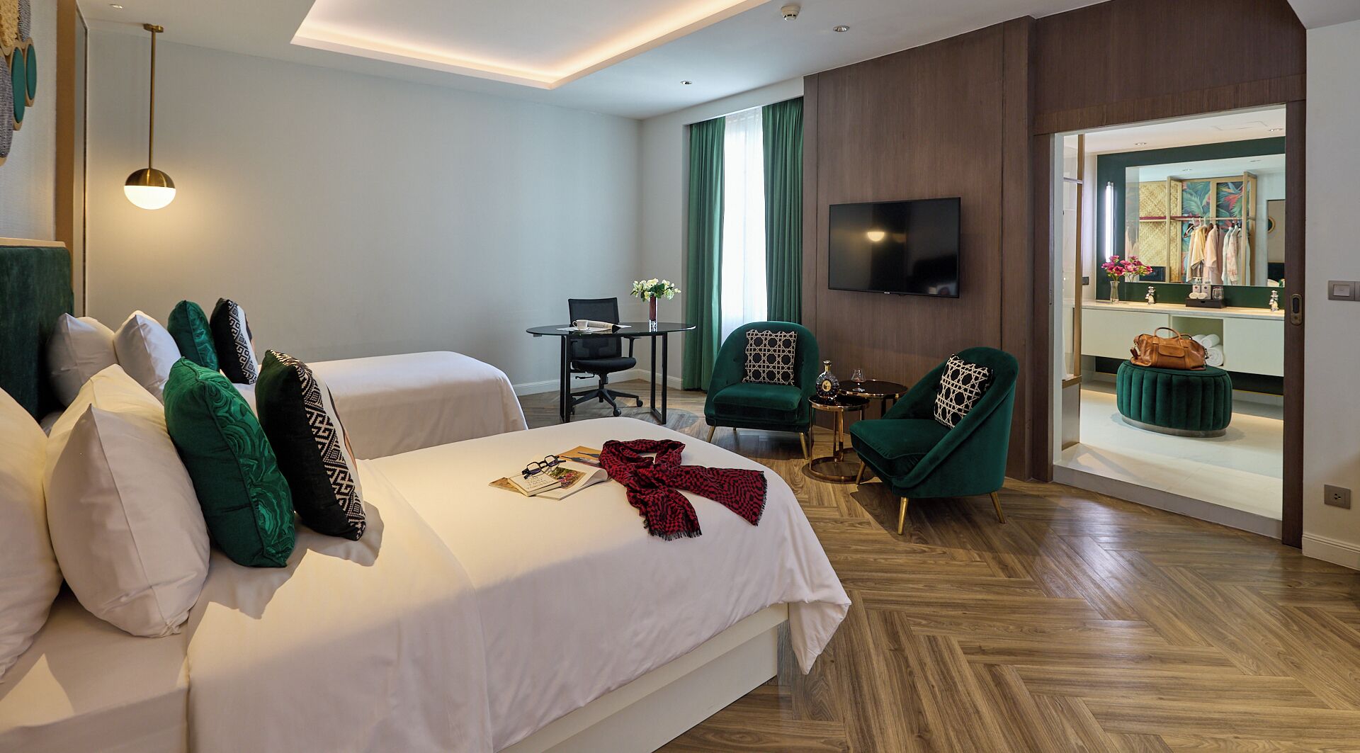 Habitación de hotel con dos camas, un escritorio, una silla, un televisor y vistas al exterior.
