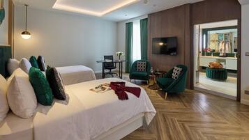 Habitación de hotel con dos camas, un escritorio, una silla, un televisor y vistas al exterior.
