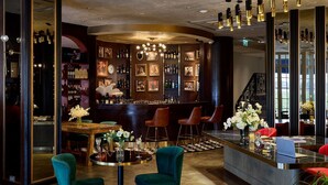 A bar area with a round table, two teal chairs, a bar counter, and a staircase. - La Seine Boutique Hotel (Vientiane)