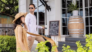 A man and a woman exiting a building with a signboard advertising happy hours. - La Seine Boutique Hotel (Vientiane)