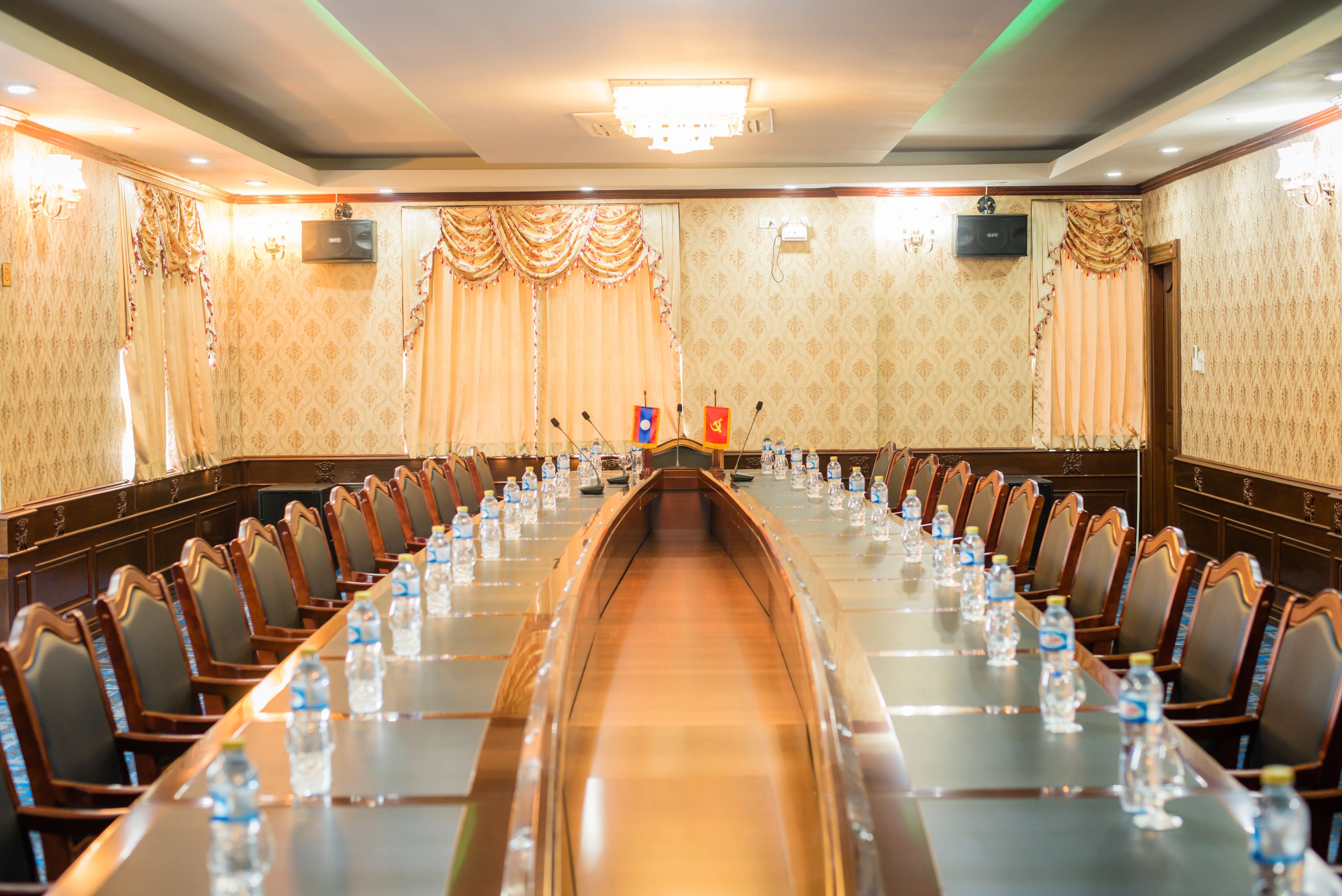 Un salón de conferencias con una larga mesa, sillas y botellas de agua.