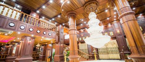 Un lobby imponente con techos altos de madera, grandes columnas y un candelabro central.
