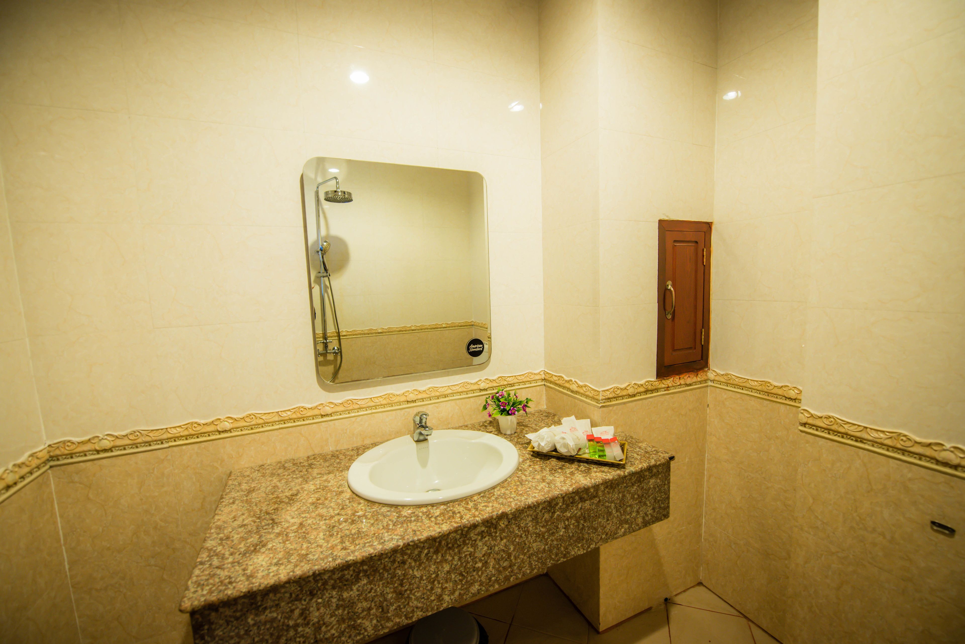 A bathroom with a granite countertop sink, a mirror, and a shower.