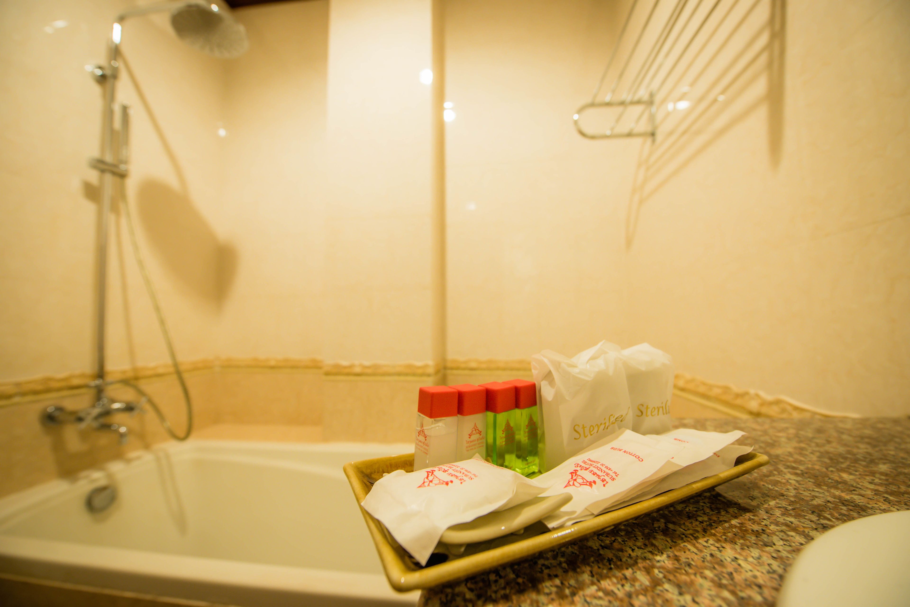 A bathroom with a bathtub, shower, and toiletries on a tray.