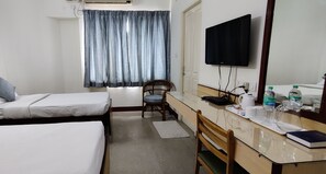 Une chambre d’hôtel avec deux lits, un bureau, une chaise, une télévision et une fenêtre avec des rideaux.