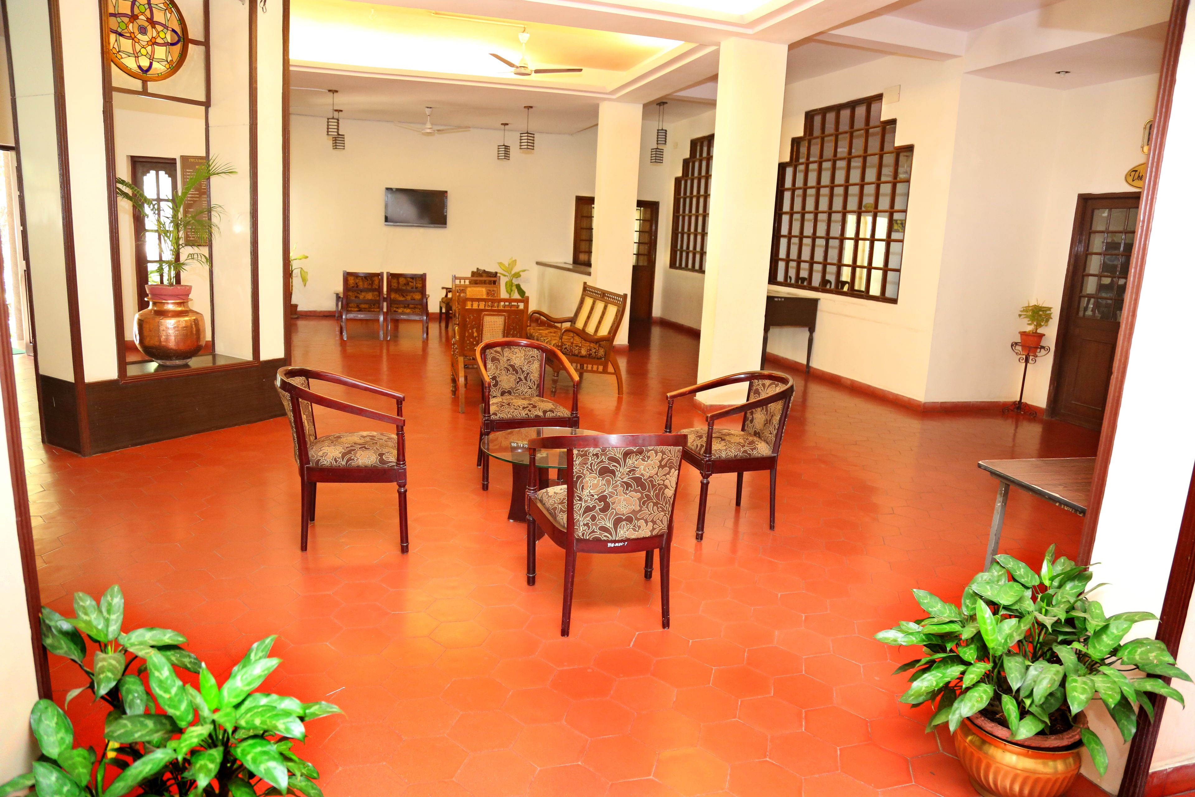 A spacious lobby with a hexagonal floor pattern, multiple seating areas, and a large decorative vase.