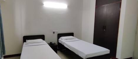 A room with two single beds, a wardrobe, and a bedside table with a phone.