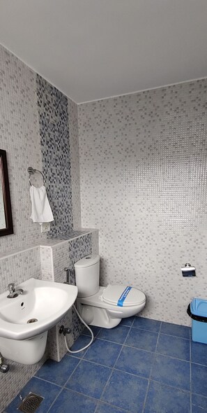 Une salle de bain avec un lavabo, un bidet, des toilettes et un sol carrelé de carreaux bleus.