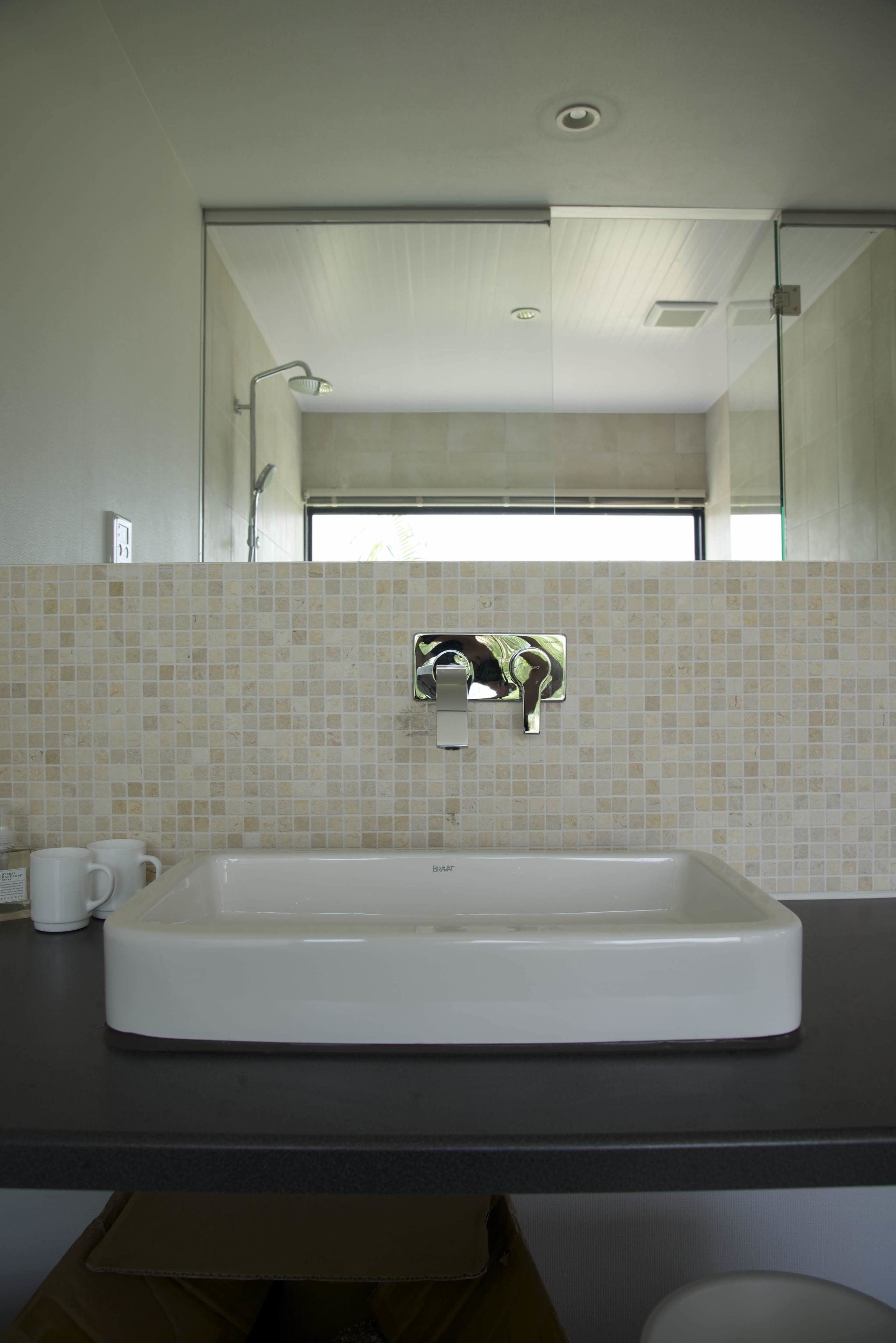 A bathroom with a white sink, a mirror, and a shower.
